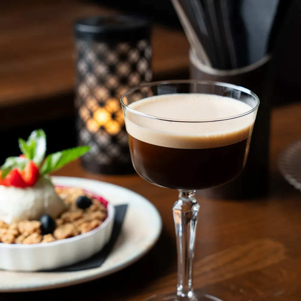 Espresso martini i coupeglas med levande ljus i bakgrunden